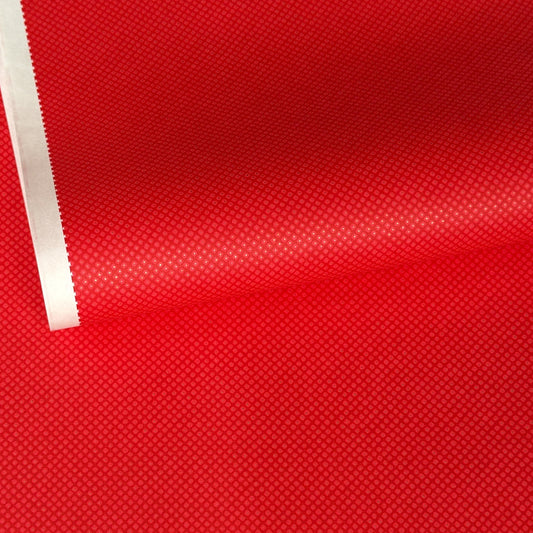 A close-up of a bright red sheet of chiyogami paper with a fine dotted pattern in gold. 