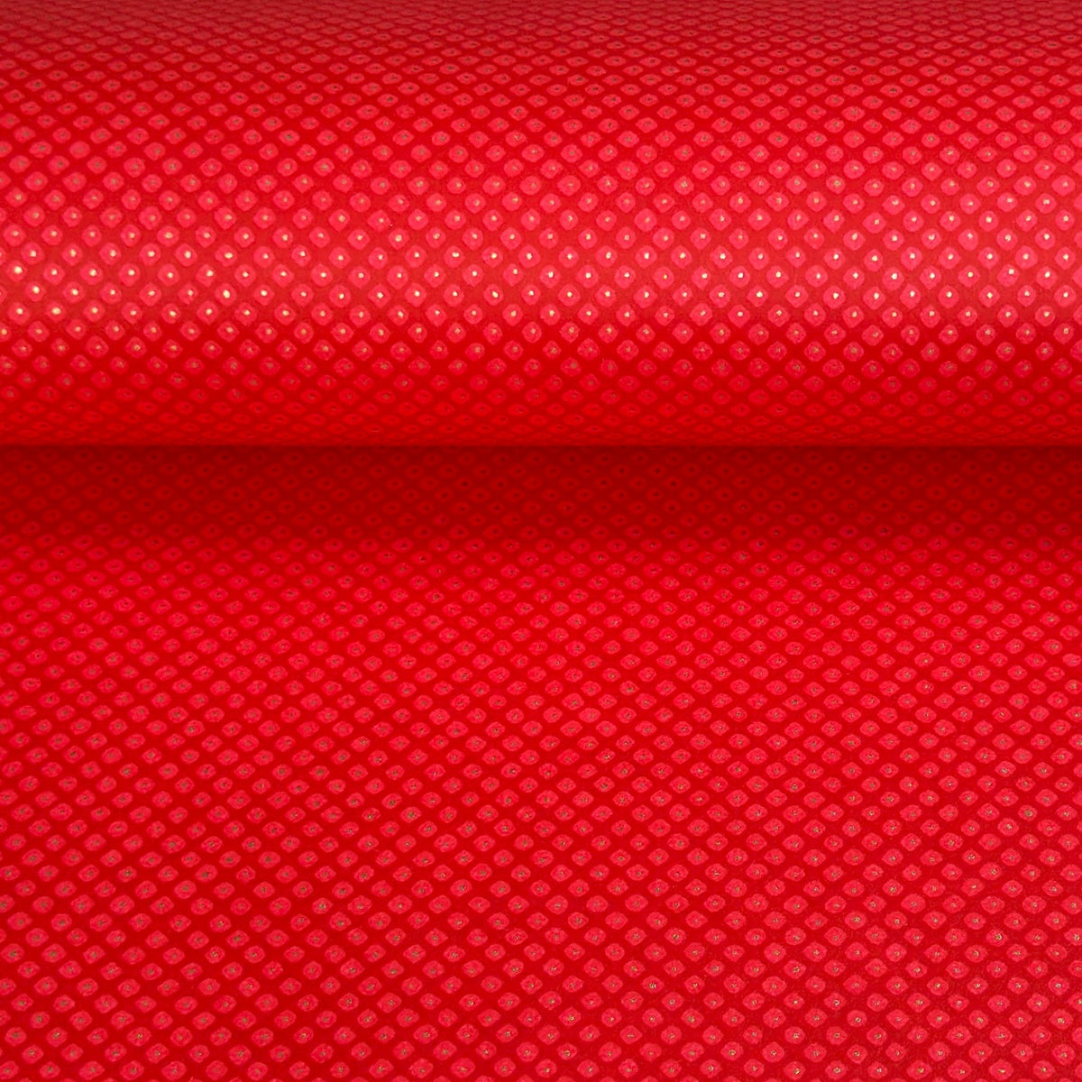 A close-up of a bright red sheet of chiyogami paper with a fine dotted pattern in gold. 