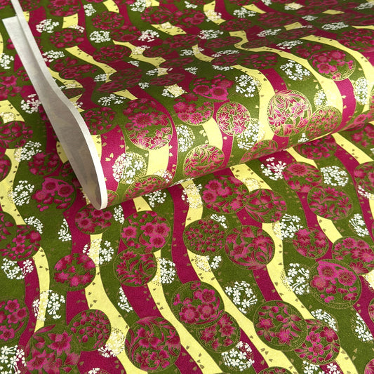 a sheet of Japanese chiyogami yuzen paper with wavy stripes in magenta, green and yellow, overlaid with circles with delicate flowers in the middle and outlined in gold.