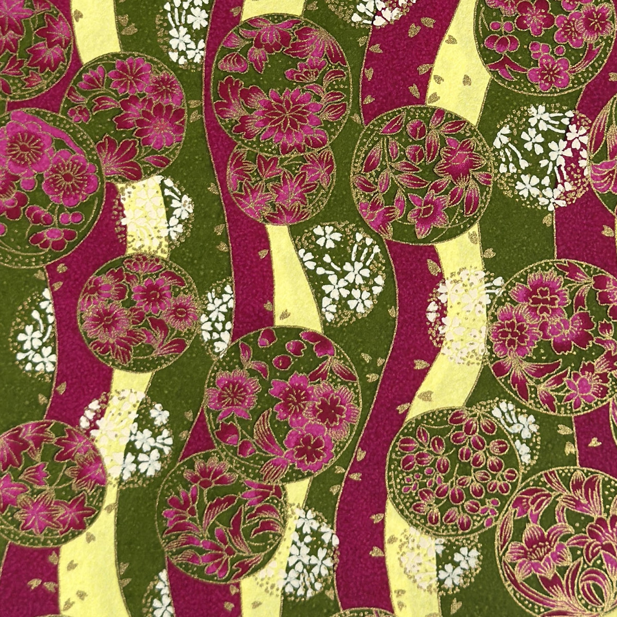 a sheet of Japanese chiyogami yuzen paper with wavy stripes in magenta, green and yellow, overlaid with circles with delicate flowers in the middle and outlined in gold.