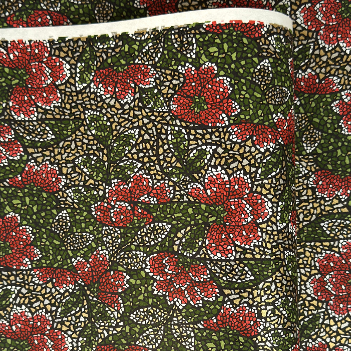 A close-up of a sheet of Japanese chiyogami paper with a repeating mosaic floral print. The design features red and flowers, green leaves on a black and gold mosaic background.