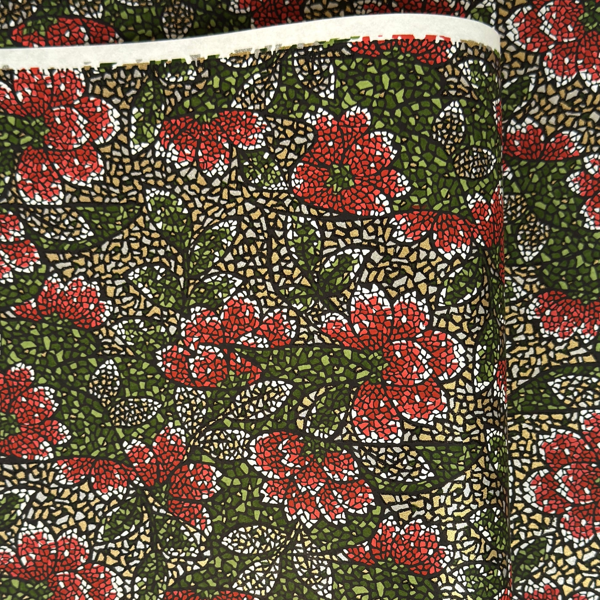 A close-up of a sheet of Japanese chiyogami paper with a repeating mosaic floral print. The design features red and flowers, green leaves on a black and gold mosaic background.