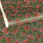 A close-up of a sheet of Japanese chiyogami paper with a repeating mosaic floral print. The design features red and flowers, green leaves on a black and gold mosaic background.