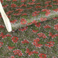 A close-up of a sheet of Japanese chiyogami paper with a repeating mosaic floral print. The design features red and flowers, green leaves on a black and gold mosaic background.