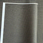 a sheet of Japanese chiyogami paper with a check plaid design in grey, black and gold
