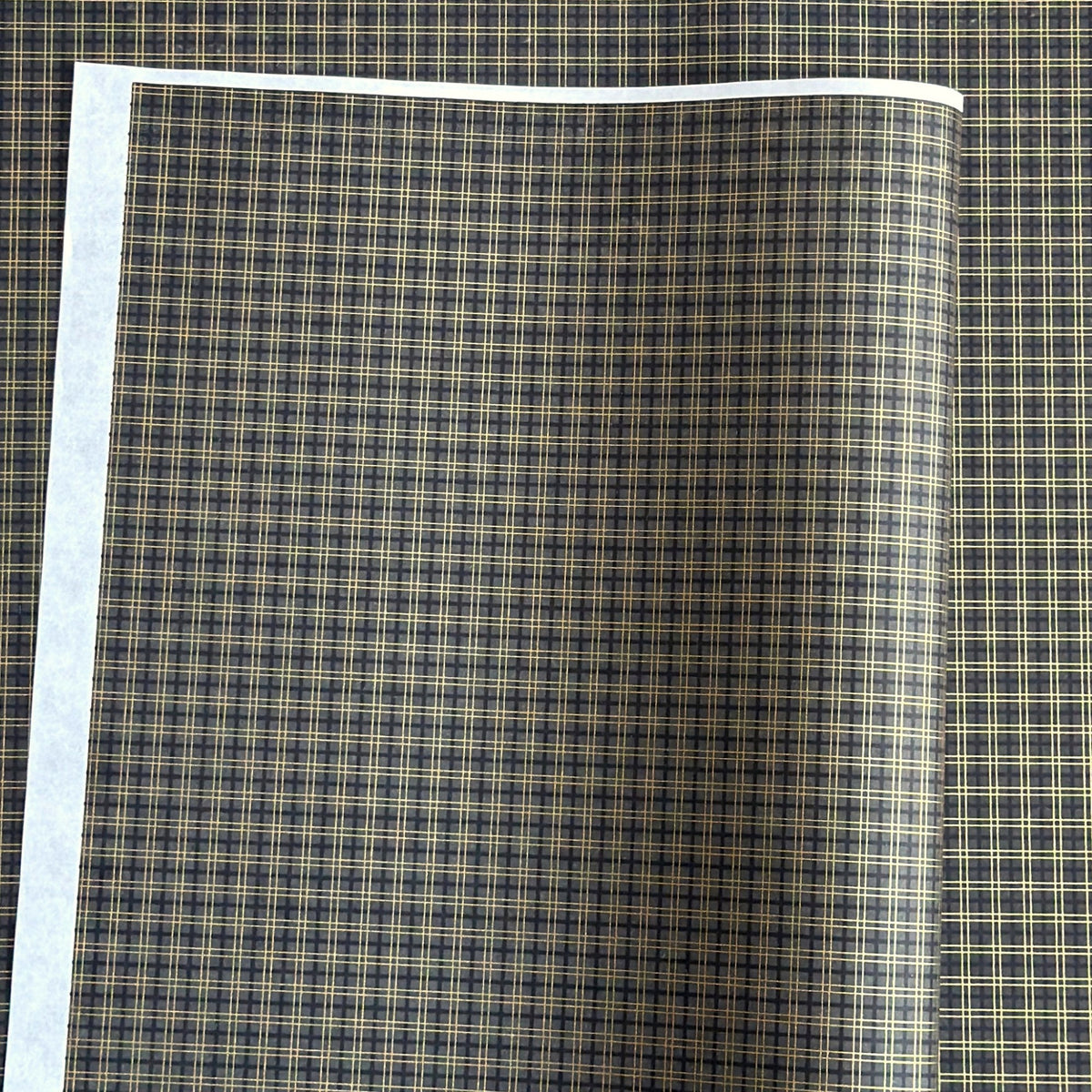 a sheet of Japanese chiyogami paper with a check plaid design in grey, black and gold