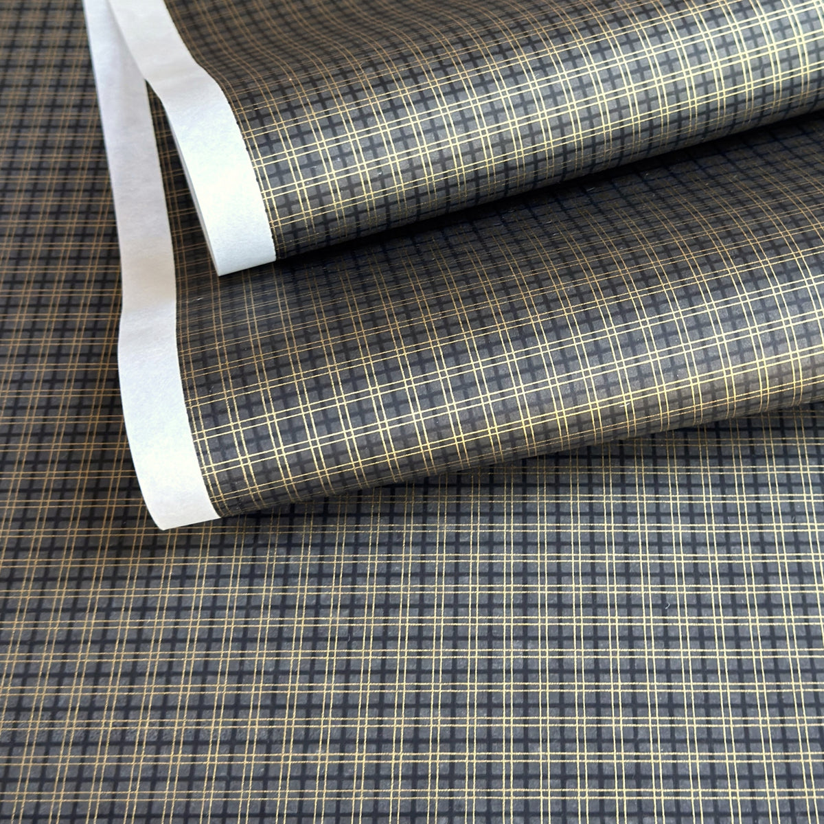 a sheet of Japanese chiyogami paper with a check plaid design in grey, black and gold