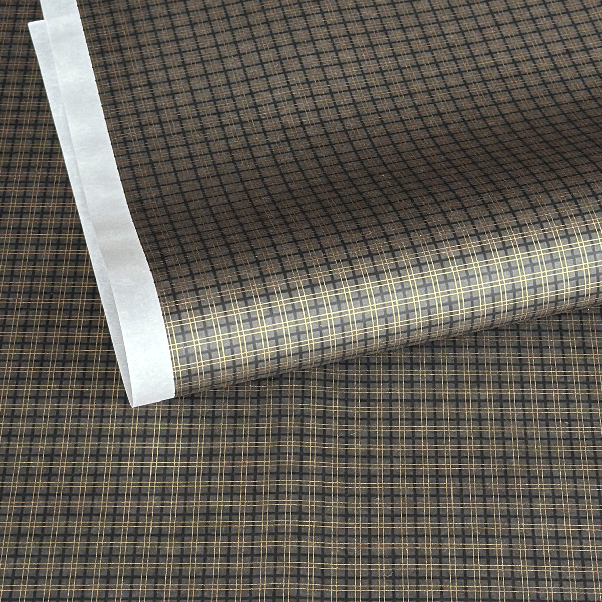 a sheet of Japanese chiyogami paper with a check plaid design in grey, black and gold