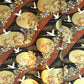 a sheet of Japanese yuzen chiyogami paper in white cranes, flowers and rivers in muted tones of autumn colours and lots of gold on a black ground.