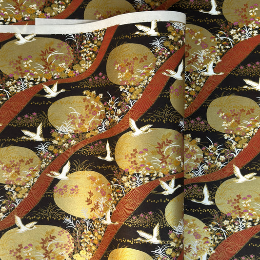 a sheet of Japanese yuzen chiyogami paper in white cranes, flowers and rivers in muted tones of autumn colours and lots of gold on a black ground.