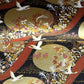 a sheet of Japanese yuzen chiyogami paper in white cranes, flowers and rivers in muted tones of autumn colours and lots of gold on a black ground.