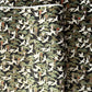 A close-up of a sheet of Japanese chiyogami paper featuring white cranes flying over green pine trees and branches on a black background.