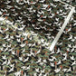 A close-up of a sheet of Japanese chiyogami paper featuring white cranes flying over green pine trees and branches on a black background.