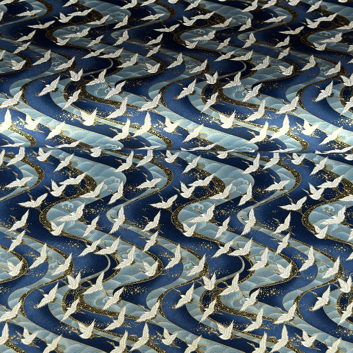 a sheet of Japanese Chiyogami paper with a hand screen printed pattern of white cranes in flight. The backdrop is swirling lines of dark and light blue with gold accents.