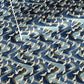 a sheet of Japanese Chiyogami paper with a hand screen printed pattern of white cranes in flight. The backdrop is swirling lines of dark and light blue with gold accents.