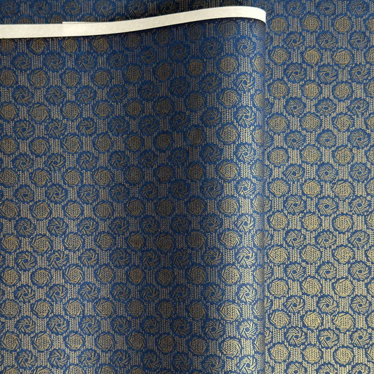 A sheet of Japanese chiyogami paper with a small repeat pattern of gold circular crests on a dark blue background.