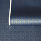 A sheet of Japanese chiyogami paper with a small repeat pattern of gold circular crests on a dark blue background.