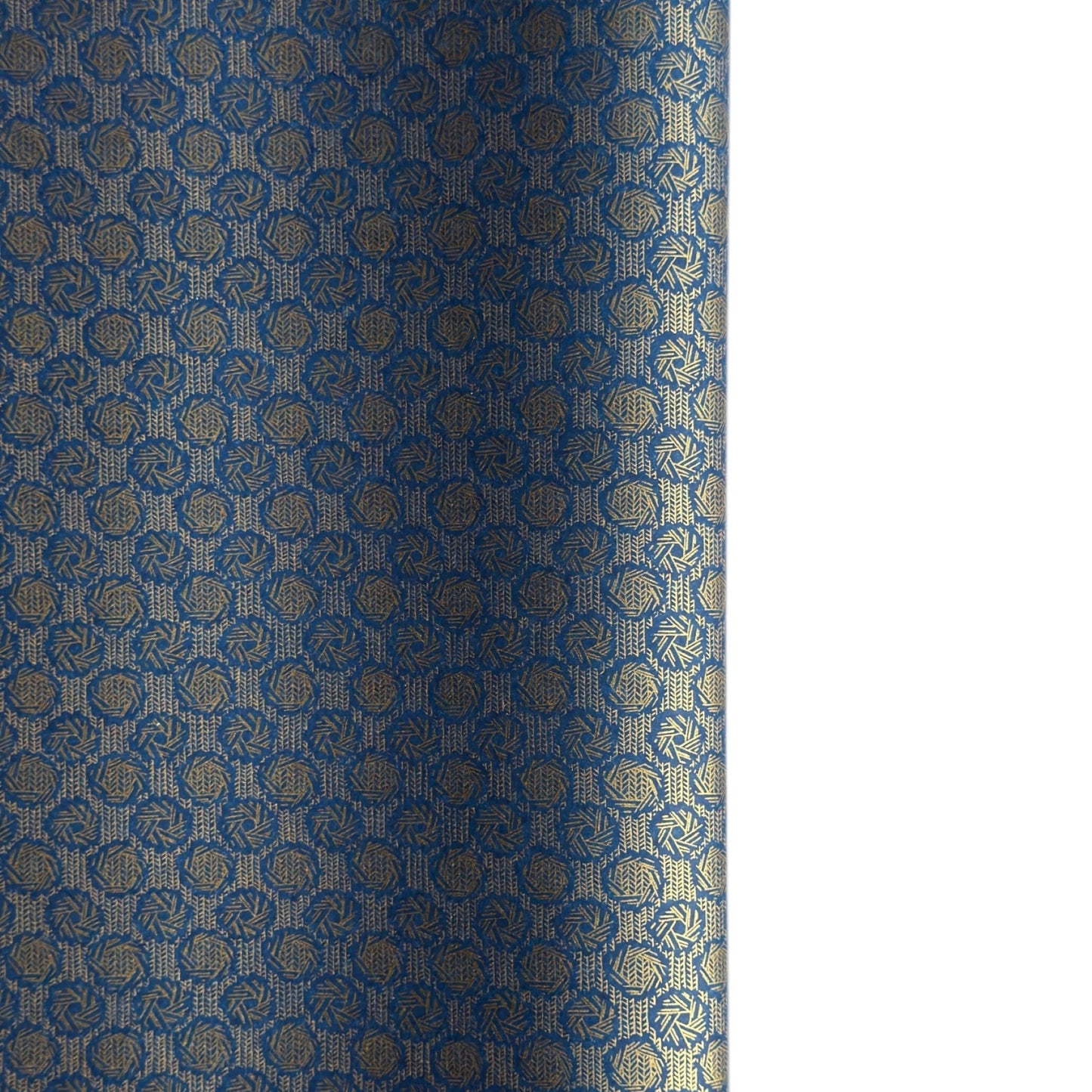 A sheet of Japanese chiyogami paper with a small repeat pattern of gold circular crests on a dark blue background.