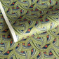 A close-up of a sheet of Japanese chiyogami paper with repeating curved wave-like motifs in olive green, navy blue, white, and small orange-red accents. 