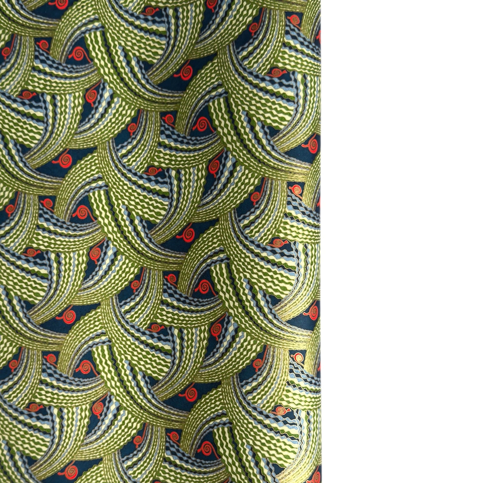 A close-up of a sheet of Japanese chiyogami paper with repeating curved wave-like motifs in olive green, navy blue, white, and small orange-red accents. 