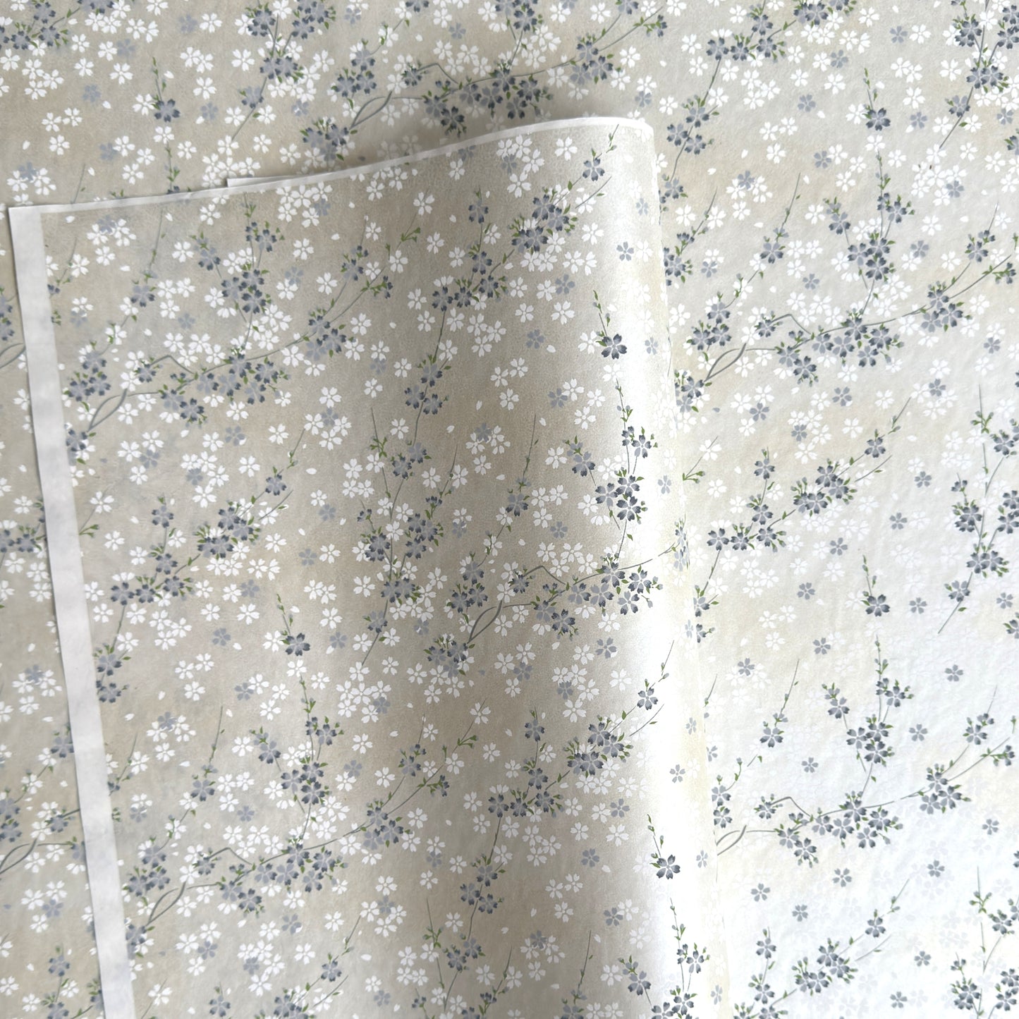 Japanese silkscreen chiyogami paper with a delicate flower design in soft grey on an ivory pearlescent backdrop