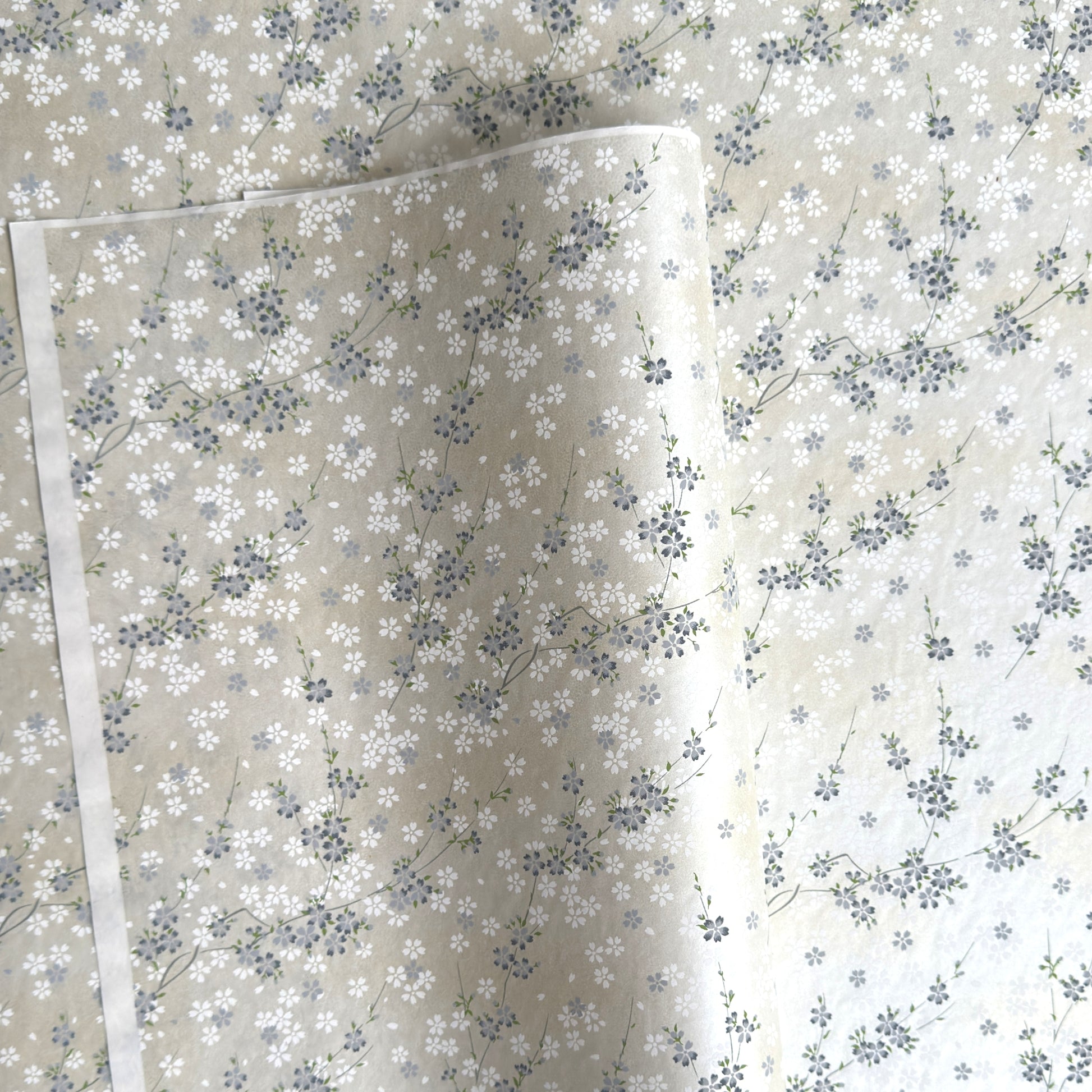 Japanese silkscreen chiyogami paper with a delicate flower design in soft grey on an ivory pearlescent backdrop