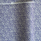 a sheet of Japanese silkscreen printed chiyogami paper with a small floral repeat pattern in grey and white on a periwinkle blue background