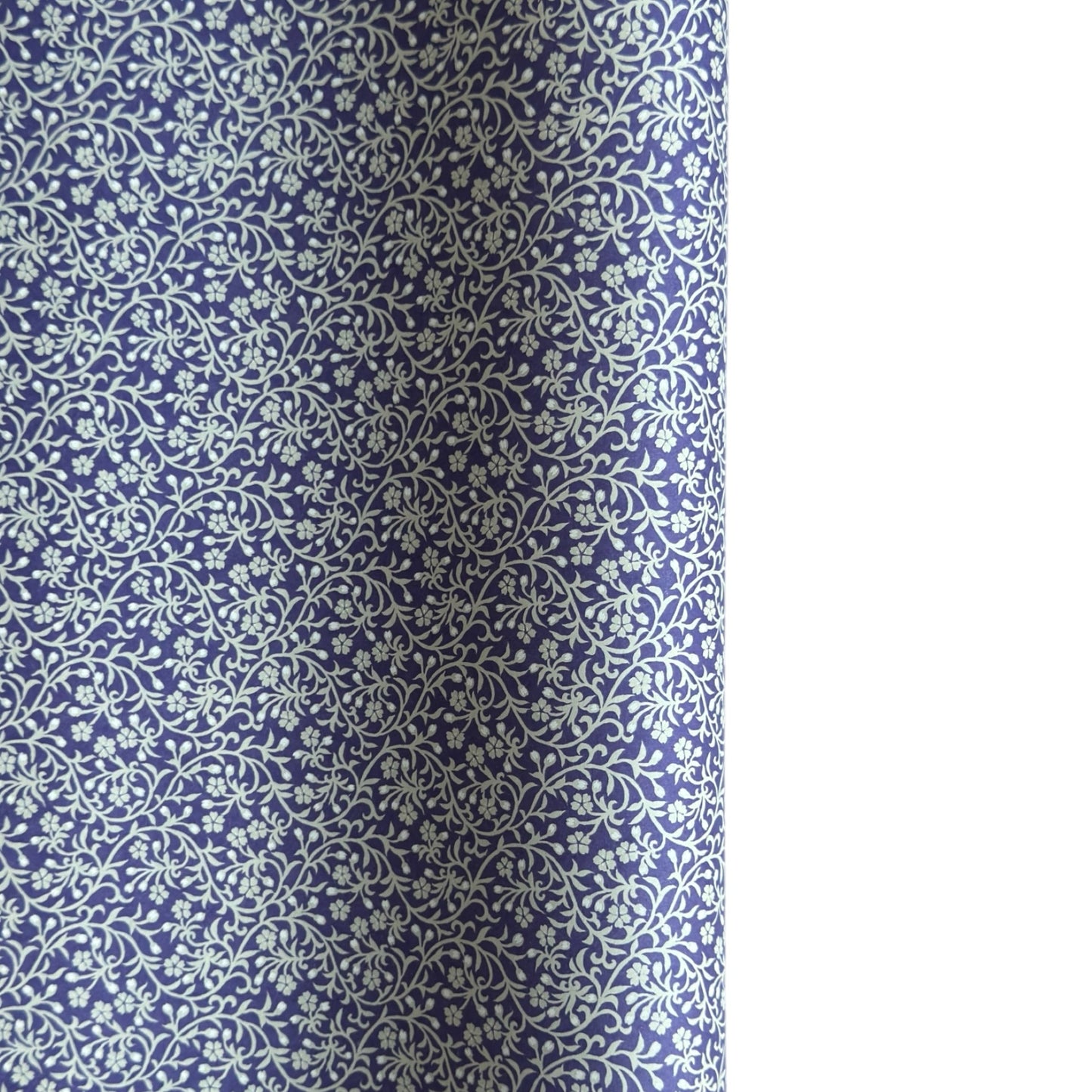 a sheet of Japanese silkscreen printed chiyogami paper with a small floral repeat pattern in grey and white on a periwinkle blue background