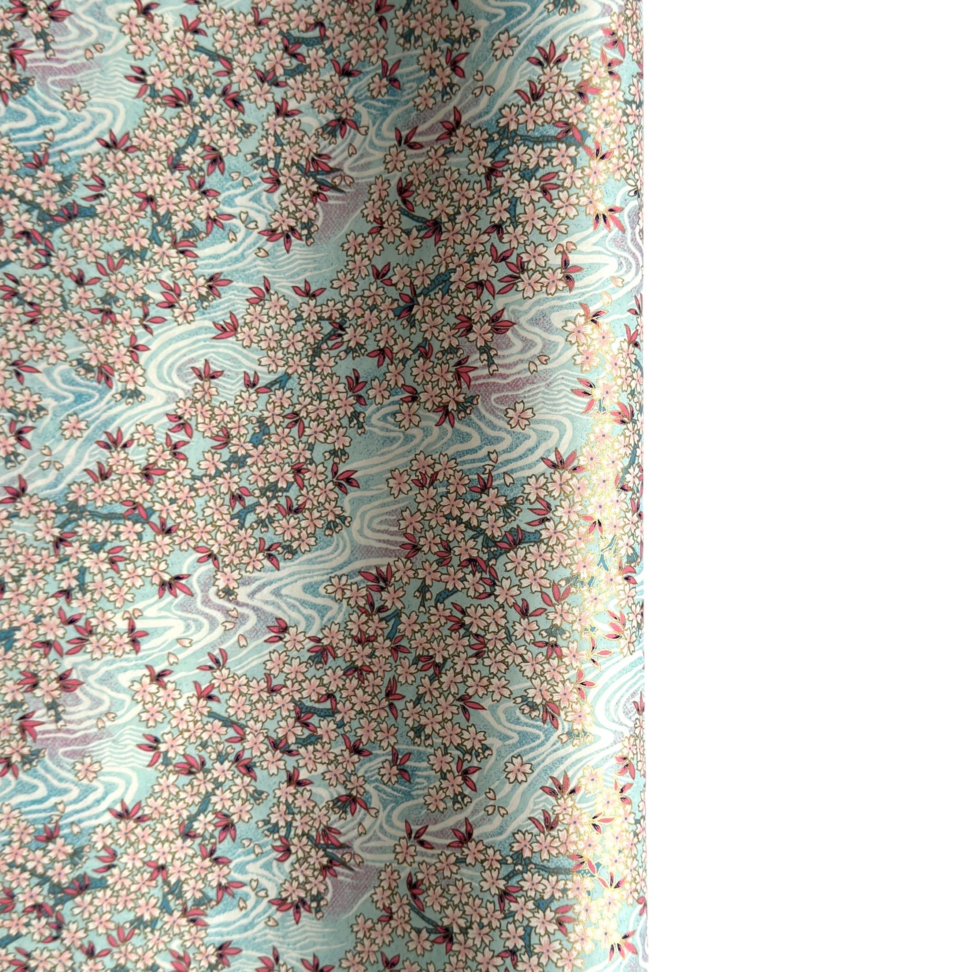 Japanese silkscreen chiyogami paper with an abundance of pale pink cherry blossom with a pale blue backdrop of meandering water, finished with metallic gold ink.