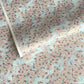Japanese silkscreen chiyogami paper with an abundance of pale pink cherry blossom with a pale blue backdrop of meandering water, finished with metallic gold ink.