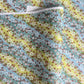 Japanese chiyogami paper silkscreened with a dainty pattern of white sakura flowers on an backdrop of aqua and lime diagonal wavy stripes
