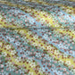 Japanese chiyogami paper silkscreened with a dainty pattern of white sakura flowers on an backdrop of aqua and lime diagonal wavy stripes