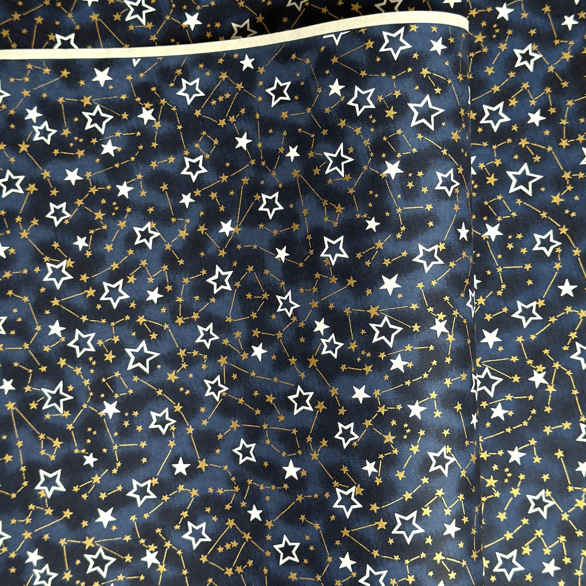 a sheet of Japanese chiyogami yuzen paper with a pattern of white and gold stars on a midnight blue background