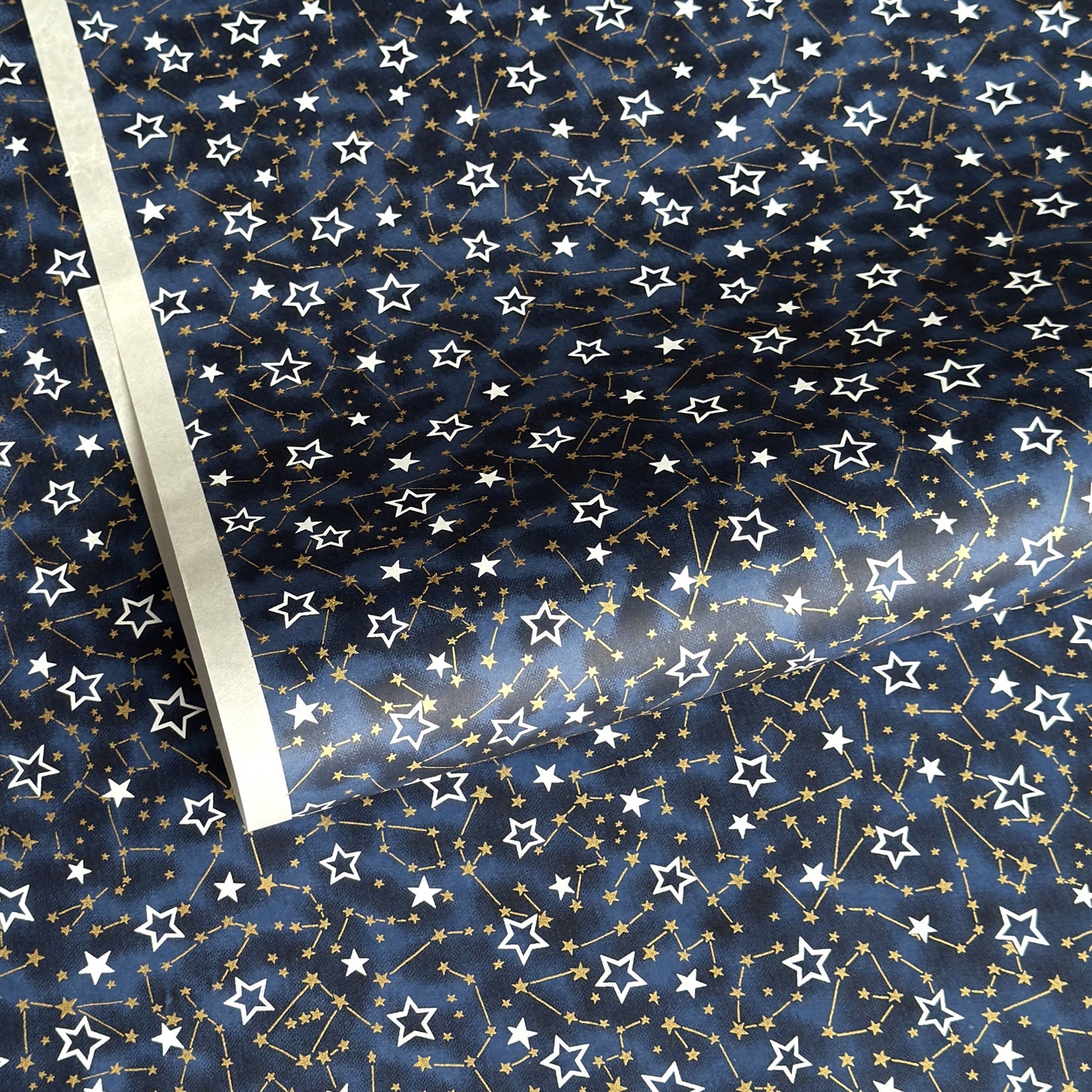a sheet of Japanese chiyogami yuzen paper with a pattern of white and gold stars on a midnight blue background