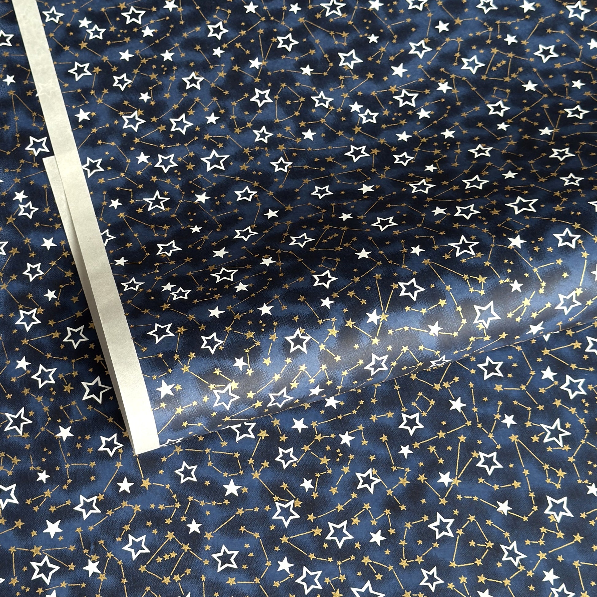 a sheet of Japanese chiyogami yuzen paper with a pattern of white and gold stars on a midnight blue background