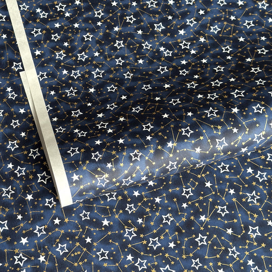 a sheet of Japanese chiyogami yuzen paper with a pattern of white and gold stars on a midnight blue background