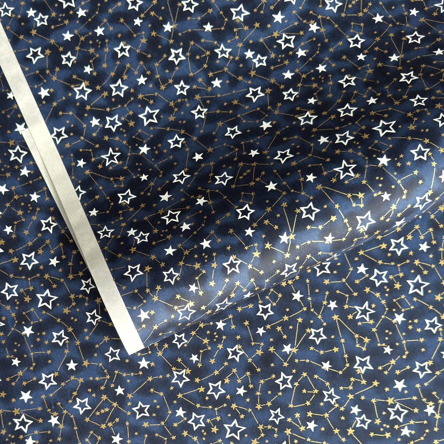 a sheet of Japanese chiyogami yuzen paper with a pattern of white and gold stars on a midnight blue background