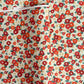 Japanese silkscreen chiyogami paper with a repeat pattern of camellia flowers in red and orange on a soft green ground