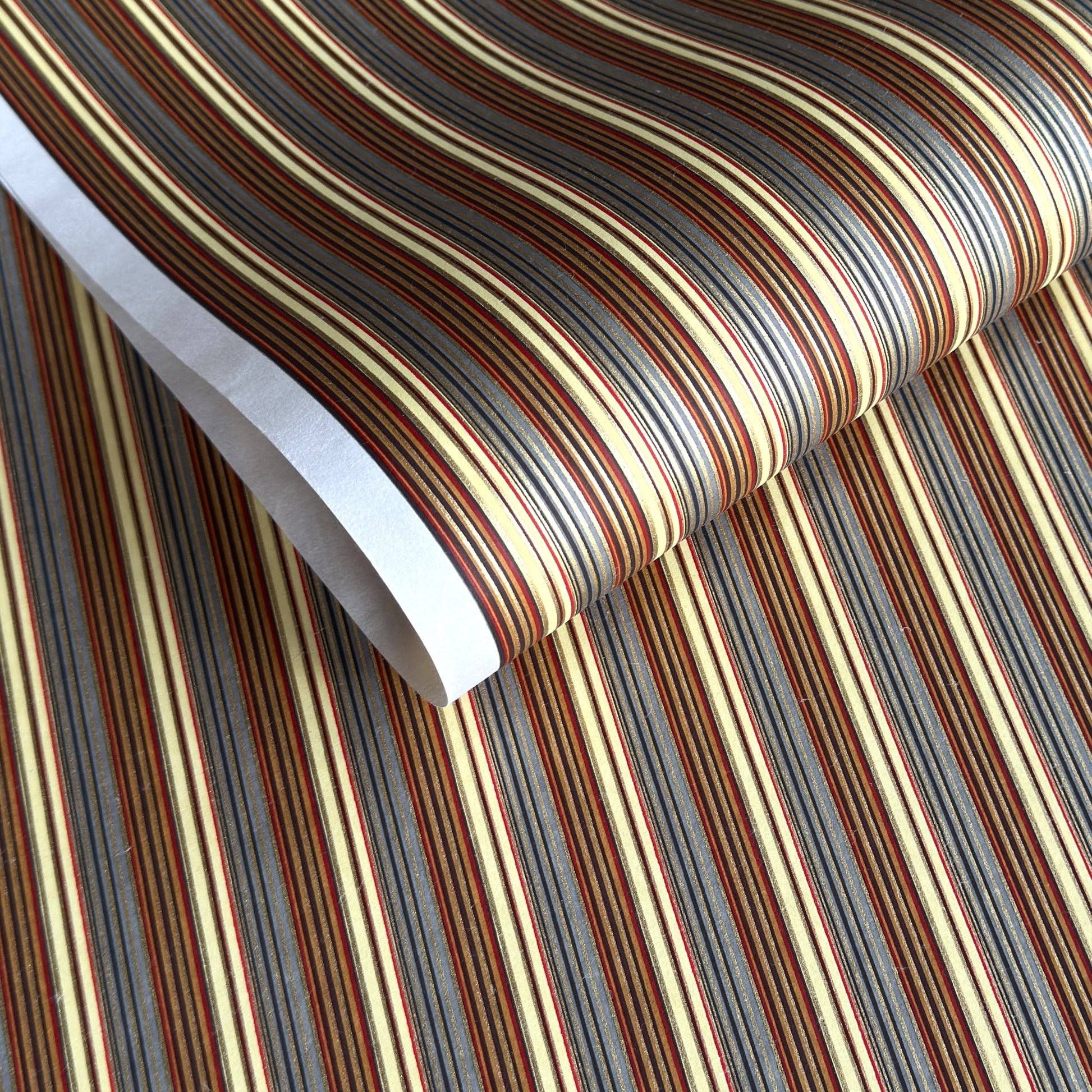 Japanese silkscreen chiyogami paper with a classic narrow stripe pattern in earthy tones of brown, grey, cream, black and gold.