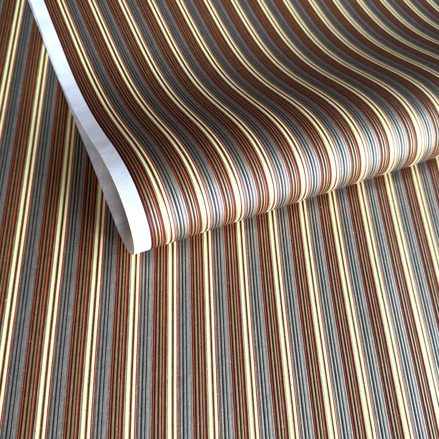Japanese silkscreen chiyogami paper with a classic narrow stripe pattern in earthy tones of brown, grey, cream, black and gold.