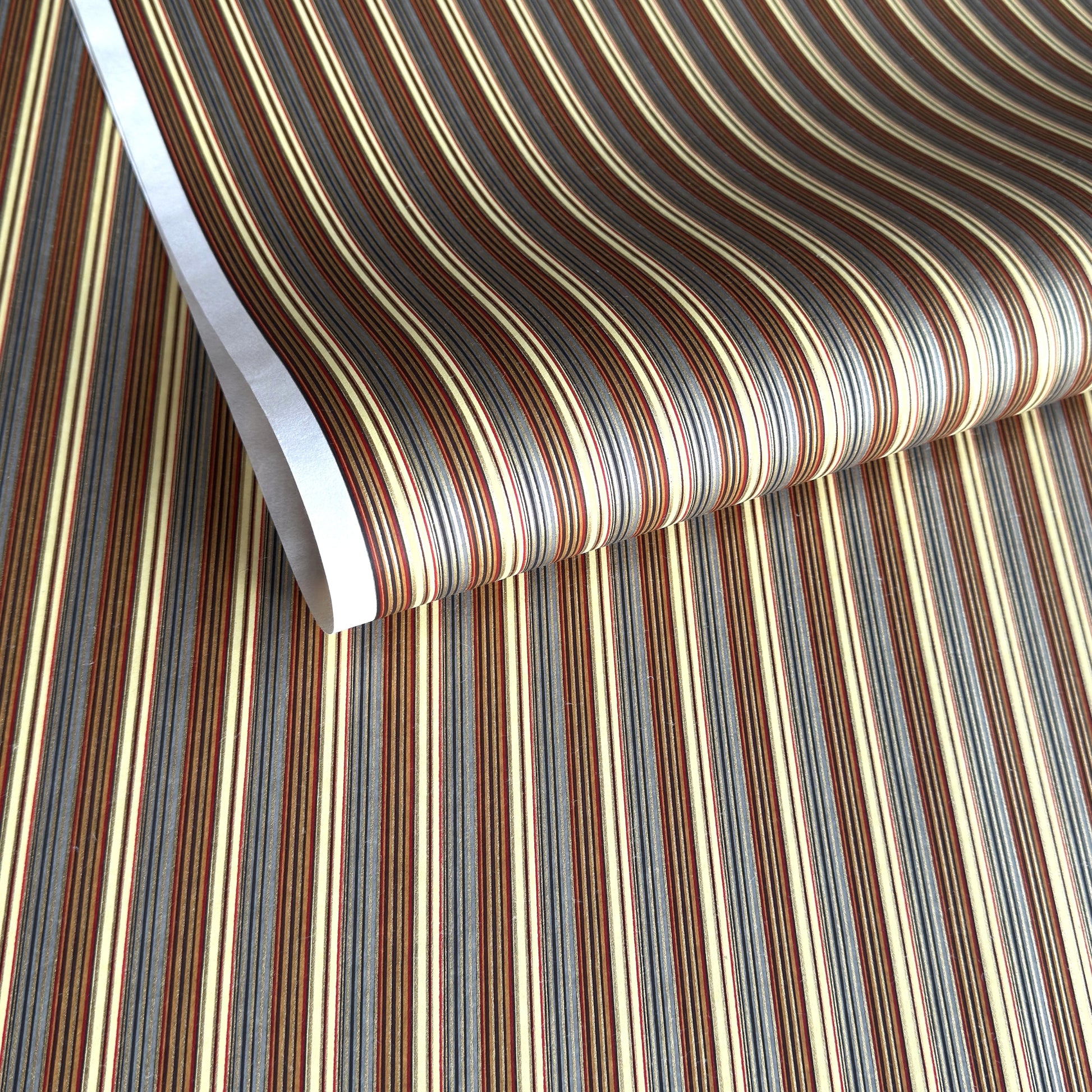 Japanese silkscreen chiyogami paper with a classic narrow stripe pattern in earthy tones of brown, grey, cream, black and gold.