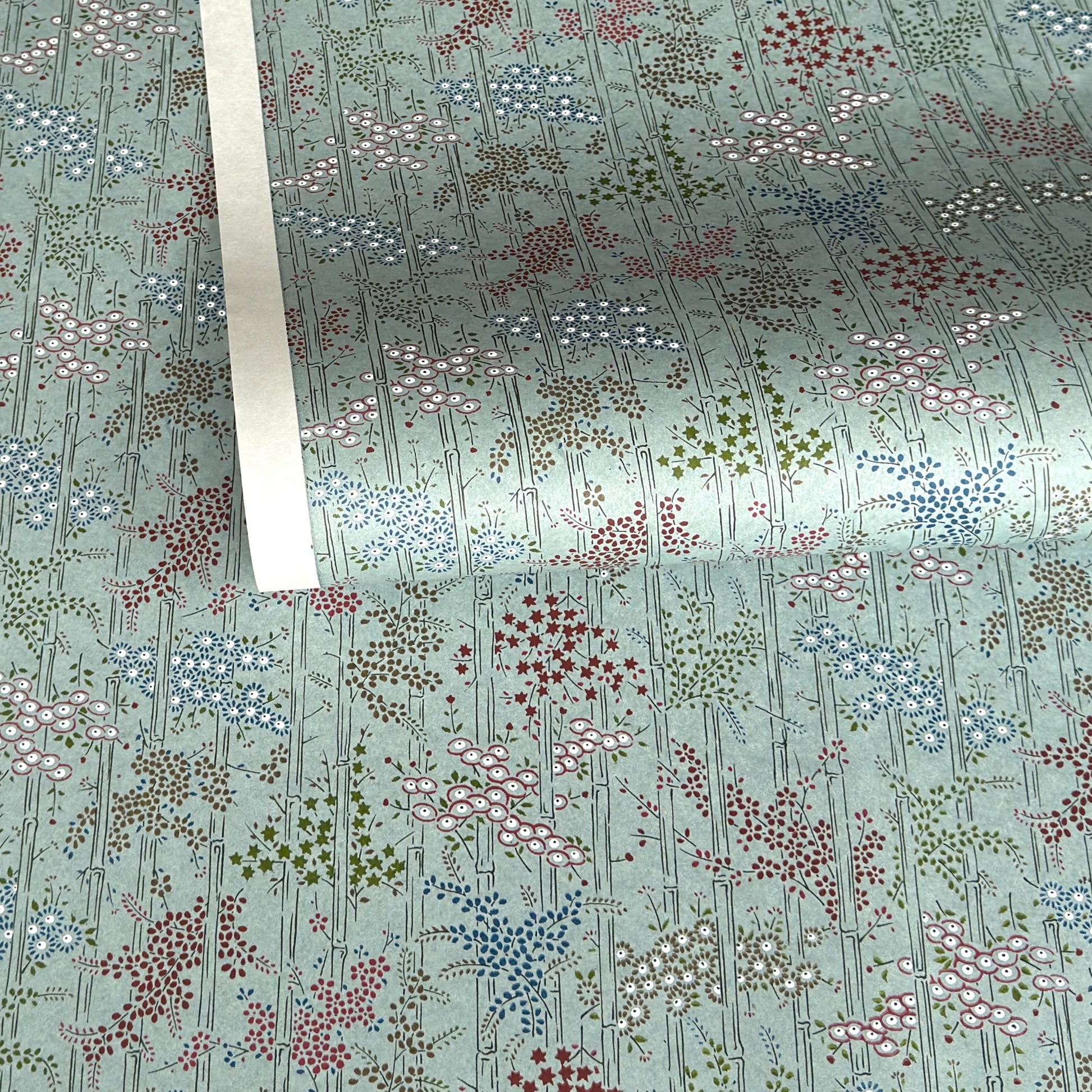 japanese silk-screen handmade paper showing pattern of bamboo, flowers and foliage on light teal backdrop