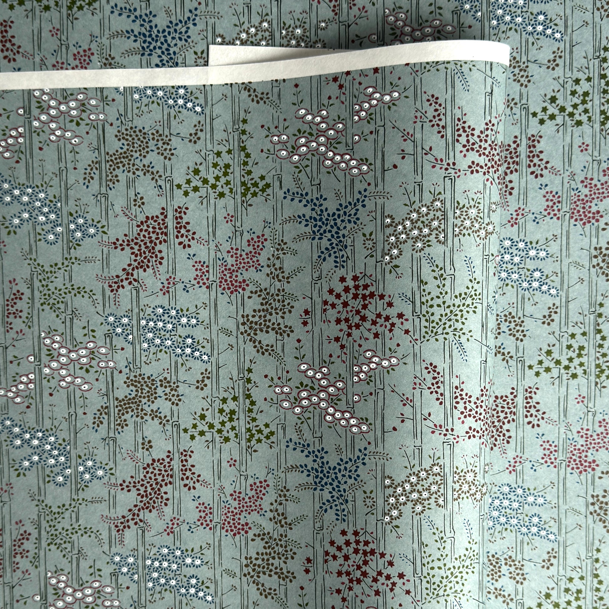 japanese silk-screen handmade paper showing pattern of bamboo, flowers and foliage on light teal backdrop