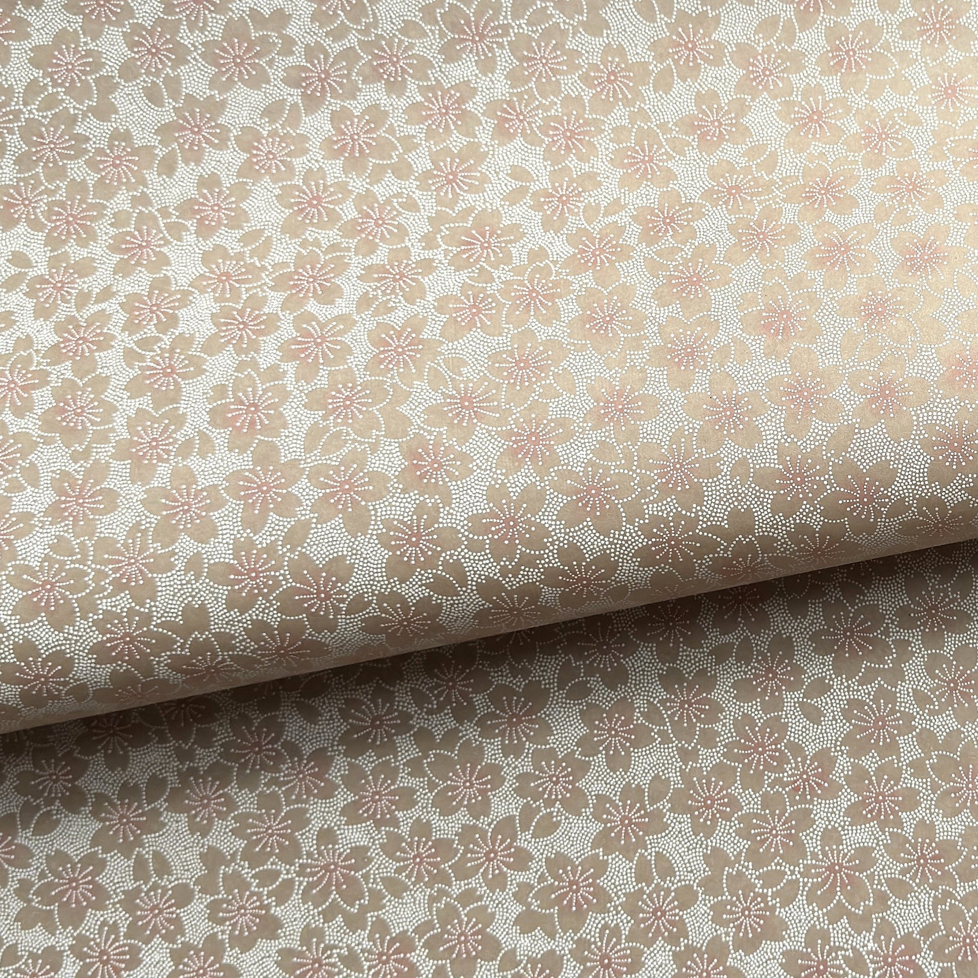 Japanese silkscreen chiyogami paper with a repeat pattern of cherry blossom flowers in taupe and white