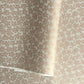 Japanese silkscreen chiyogami paper with a repeat pattern of cherry blossom flowers in taupe and white