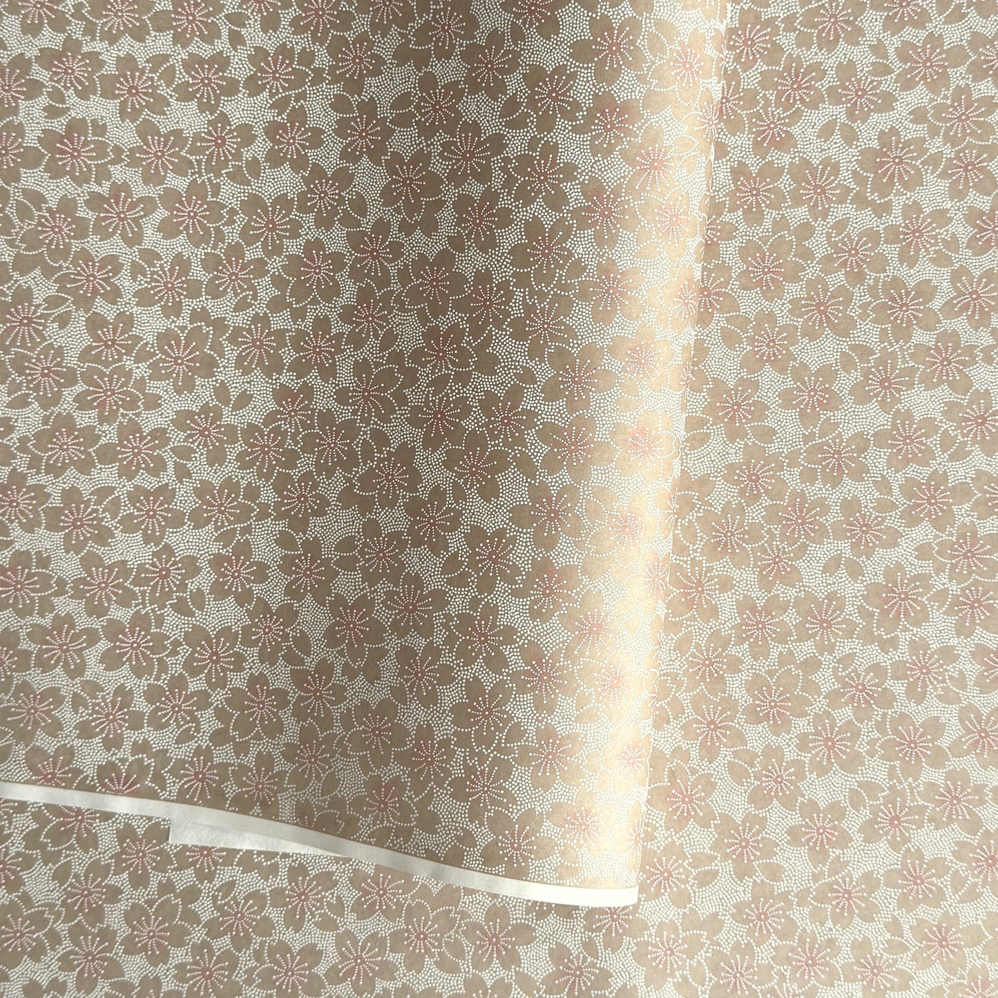 Japanese silkscreen chiyogami paper with a repeat pattern of cherry blossom flowers in taupe and white