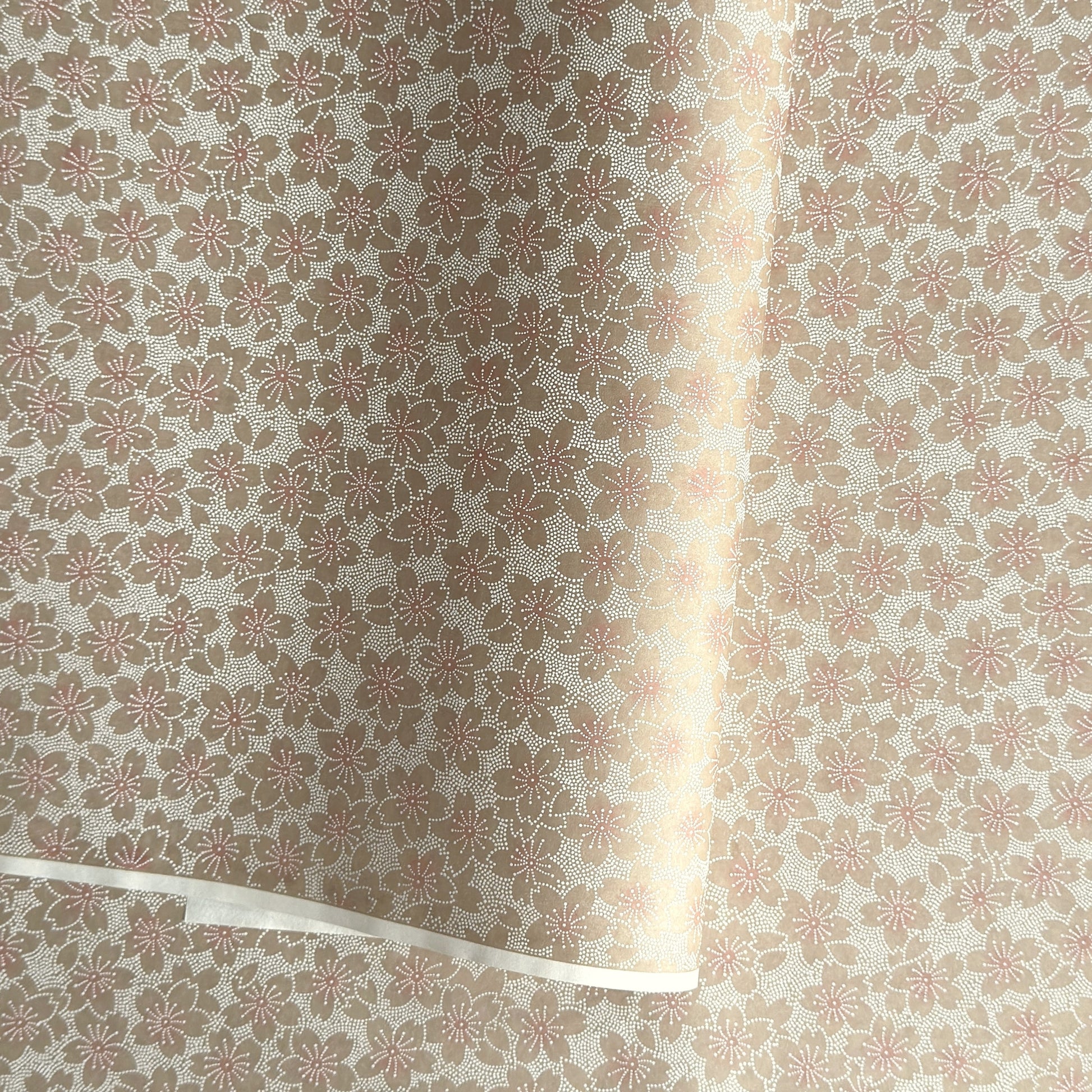 Japanese silkscreen chiyogami paper with a repeat pattern of cherry blossom flowers in taupe and white