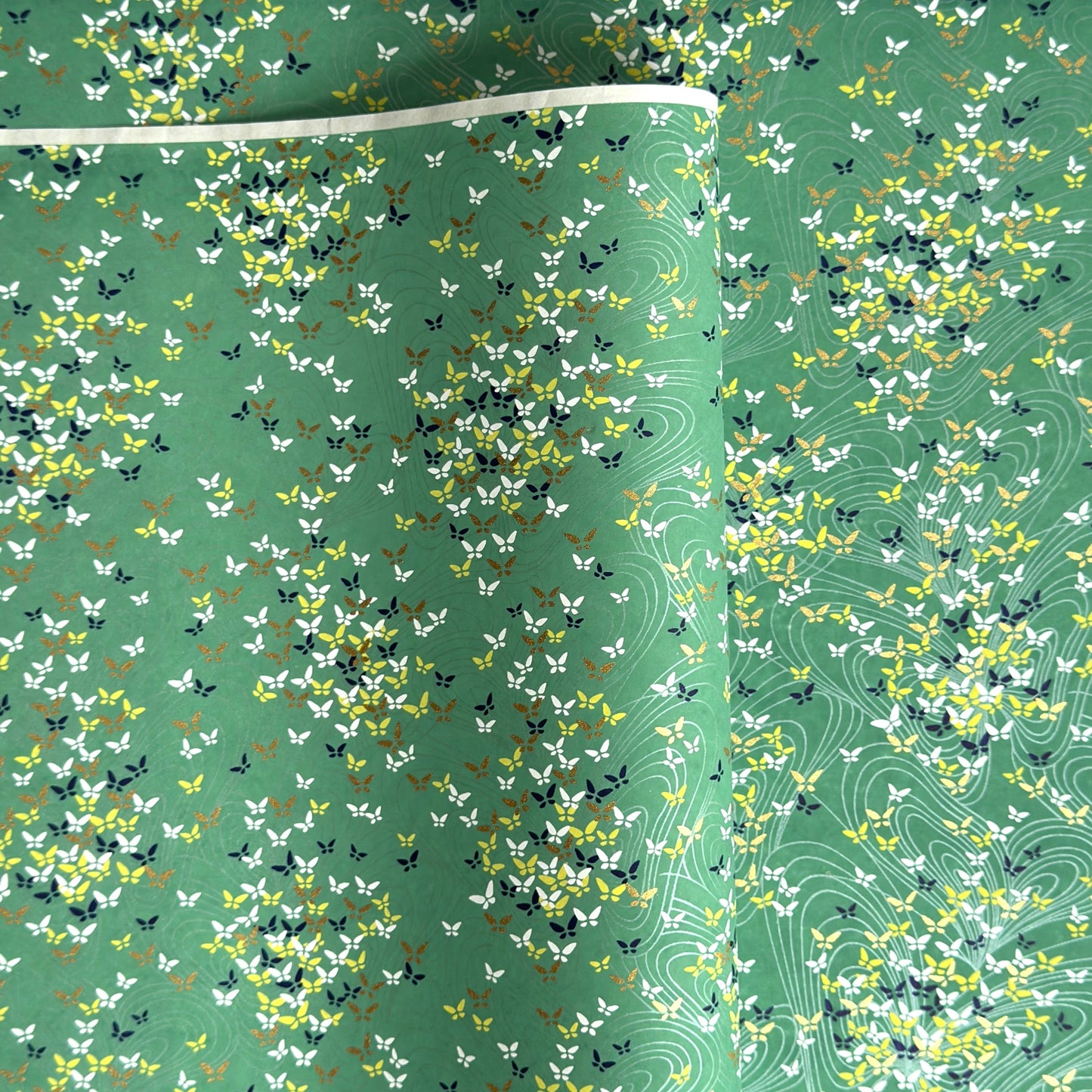 Japanese silkscreen chiyogami paper with a delicate butterfly pattern on a teal backdrop