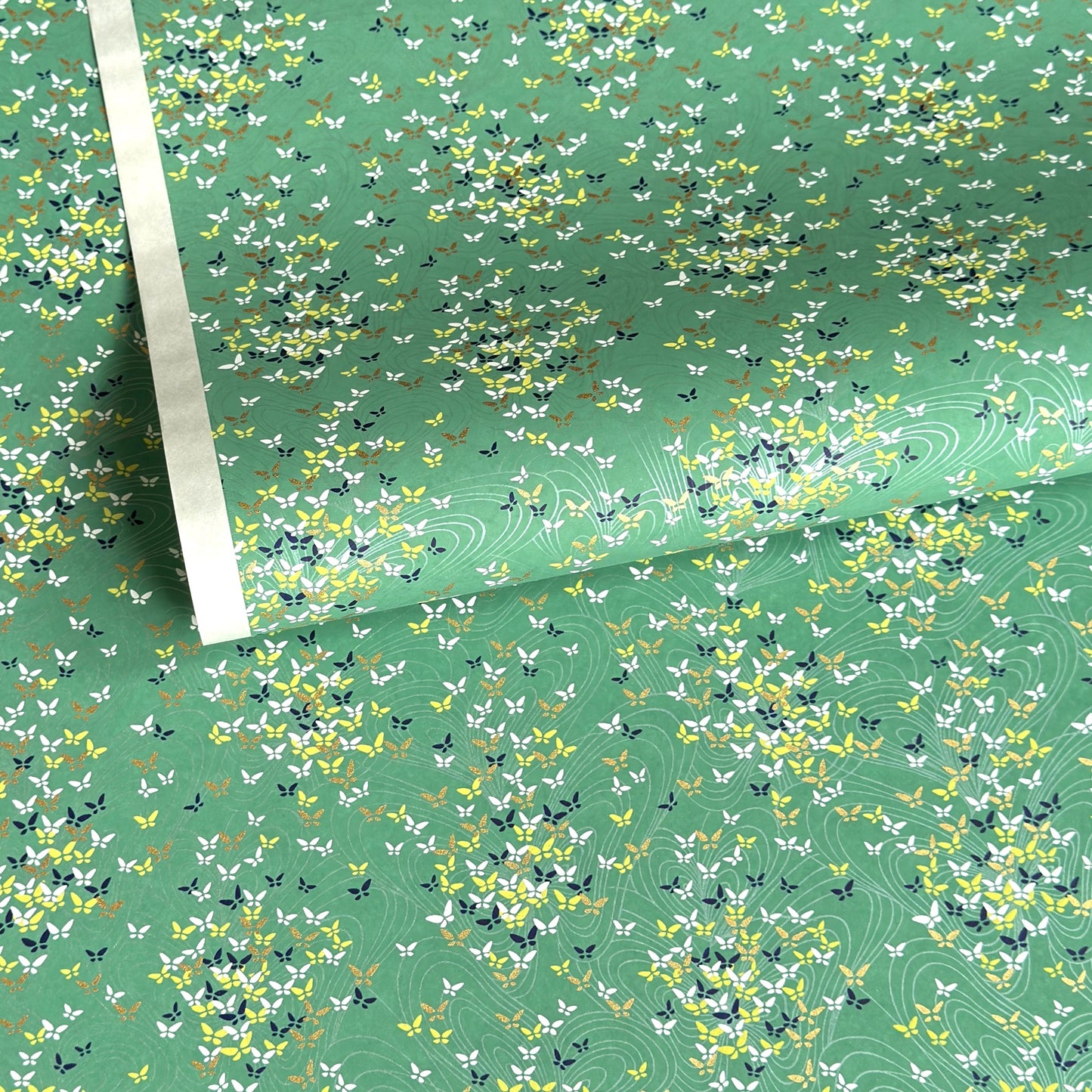 Japanese silkscreen chiyogami paper with a delicate butterfly pattern on a teal backdrop