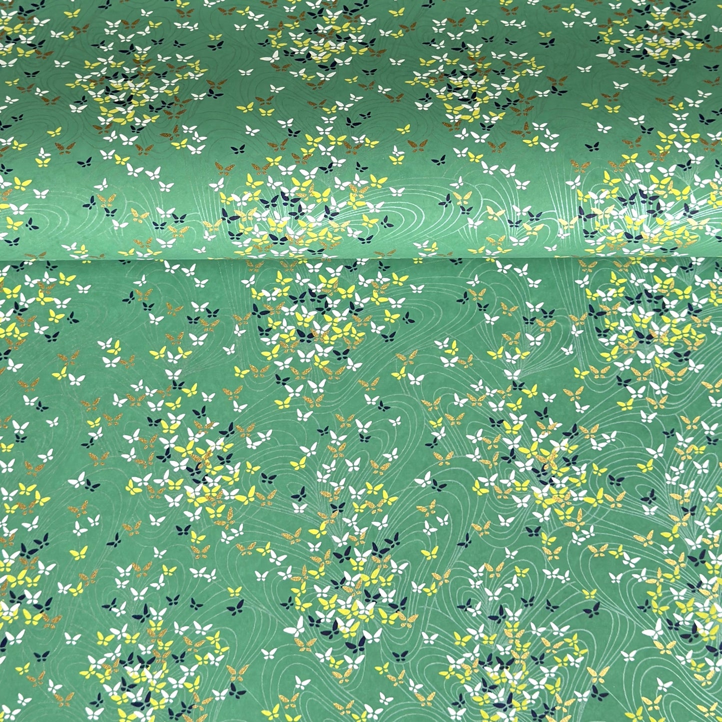 Japanese silkscreen chiyogami paper with a delicate butterfly pattern on a teal backdrop